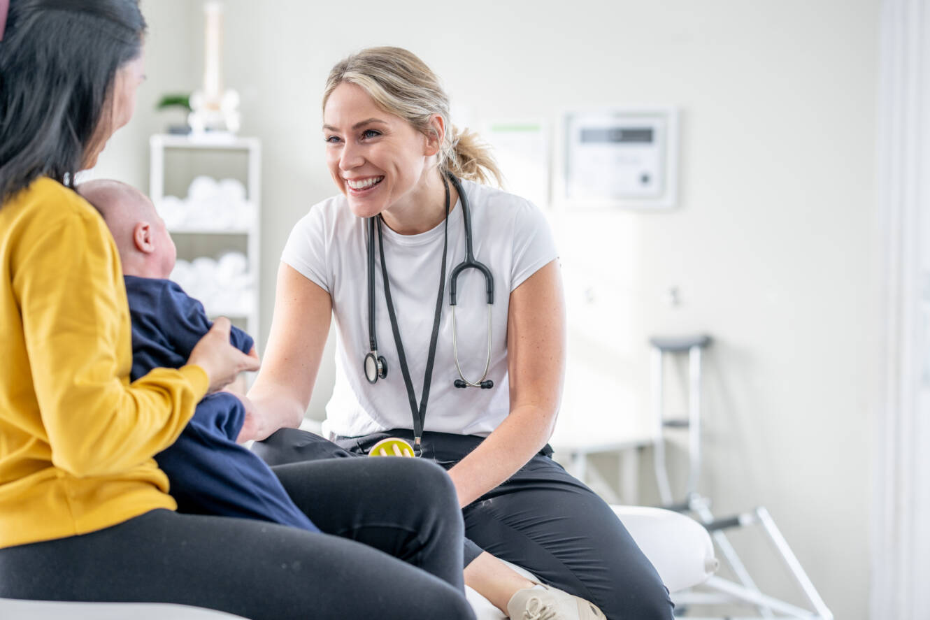 Doctor smiling with mom and baby in office exam